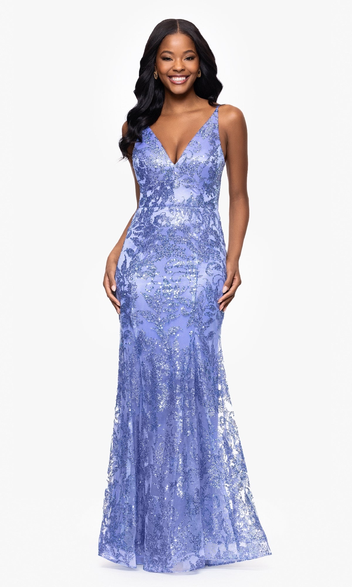 A woman stands smiling against a white background, wearing the Blondie Nites 4501BN long sequin-print prom dress with a sleeveless V-neckline and strappy-back detail.